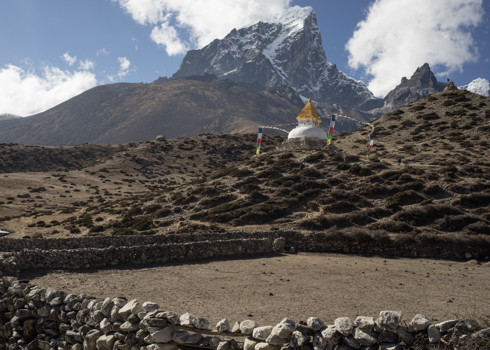Rocks are stacked without mortar to create fences to contain yak during the night after grazing and to outline yards around homes. You can see a patchwork of trails made by yak leading up to the Stupa and beyond to their grazing areas. Taboche 6,495 m / 21,309 ft. 