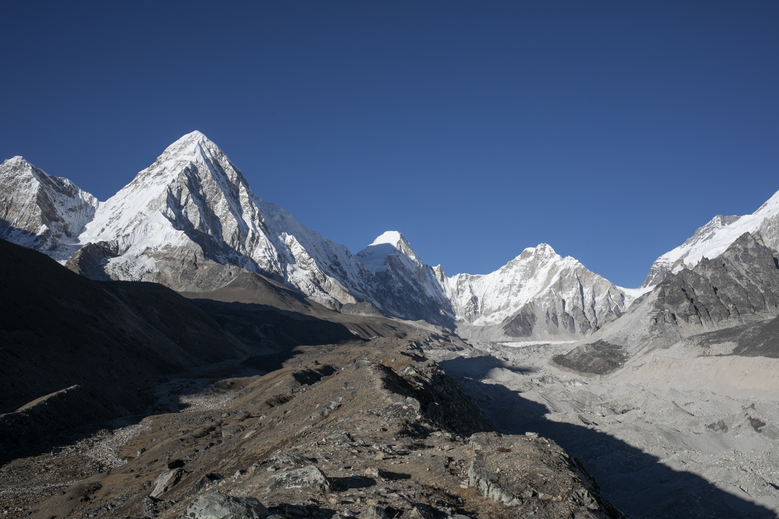 Hiking atop the rocky glacial moraine we could see farther down the valley. The proximity to the glacier quickly dropped the temperature. We could see small patches of ice peaking out from the gravel. Left to Right: Chumbu 6,859 m / 22,503 ft, Pumori 7,161 m / 23,494 ft, Lingtren 7,161 m / 23,494 ft, Khumbutse 6,636 m / 21,772 ft, Nuptse 7,861 m / 25,791 ft.