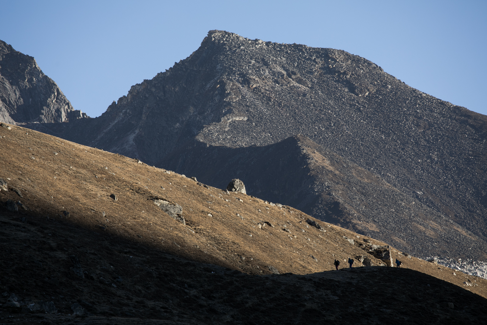 Porters become sillhouetted as the sun moves behind a peak. 