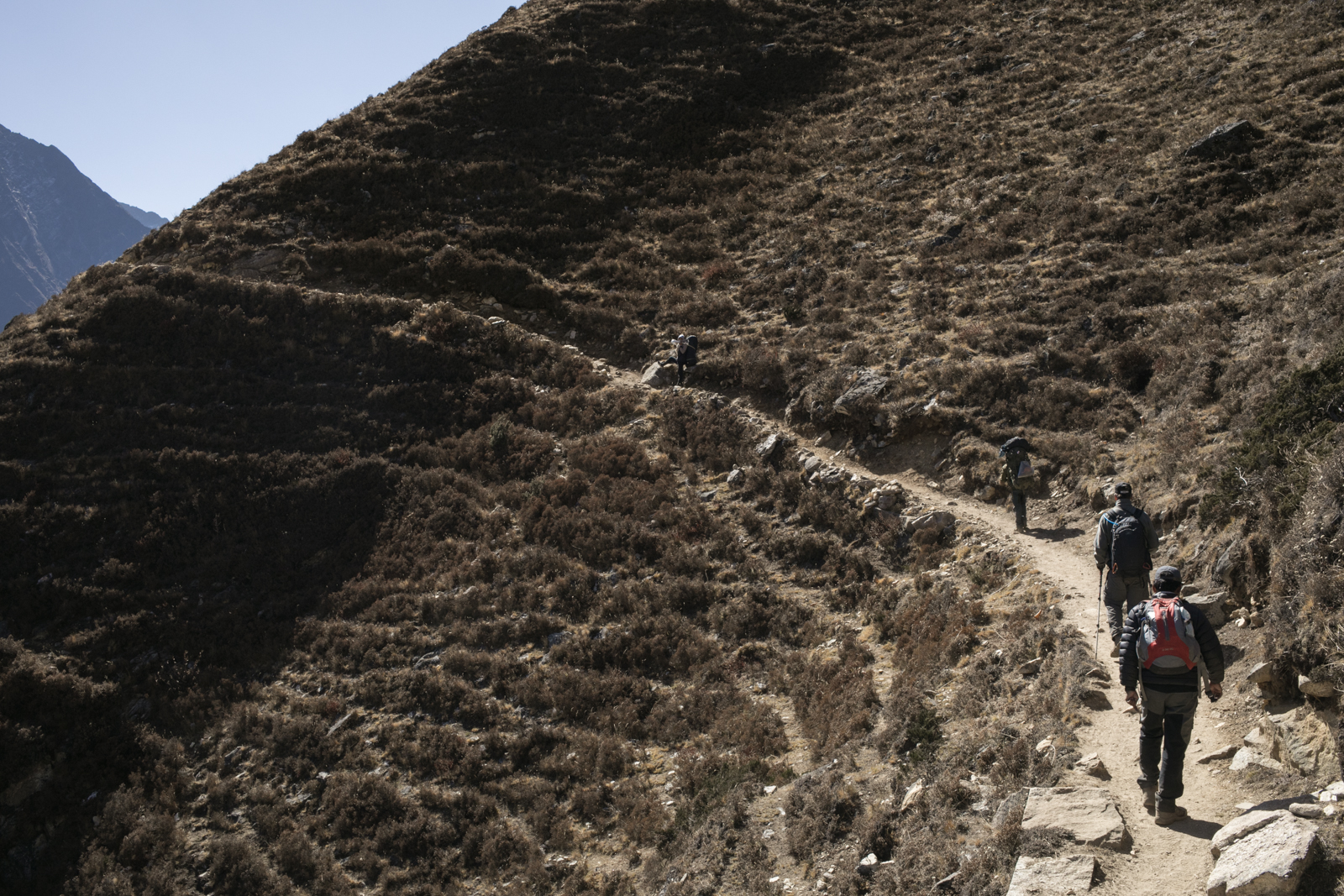 Traversing along a narrow path high on a steep slope. The trail looked like a thin scratch following the landscape. 