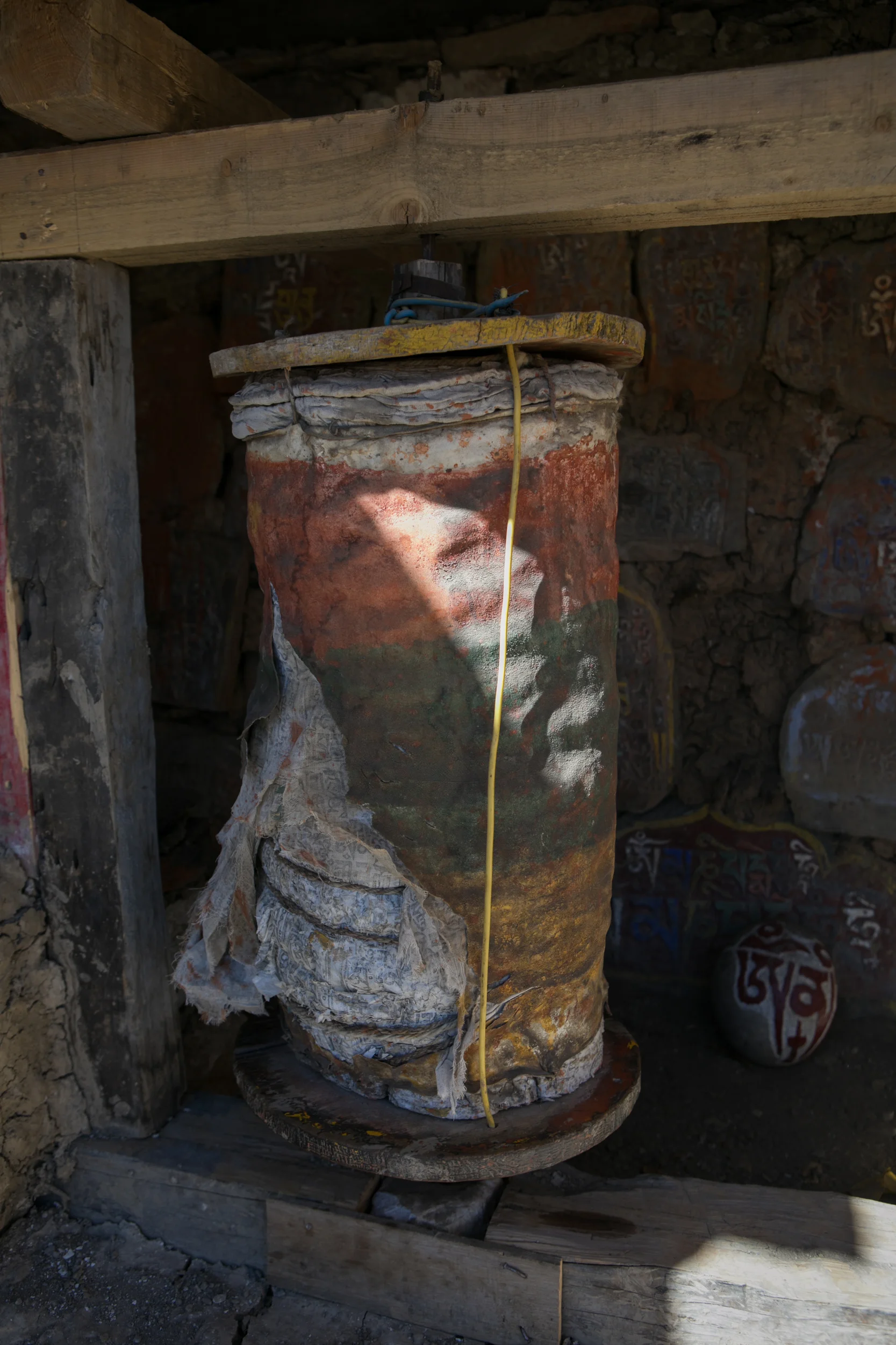 An ancient prayer wheel that is split. You can see the rounds of cloth that fill the inside of a prayer wheel with prayers written across the fabric. 