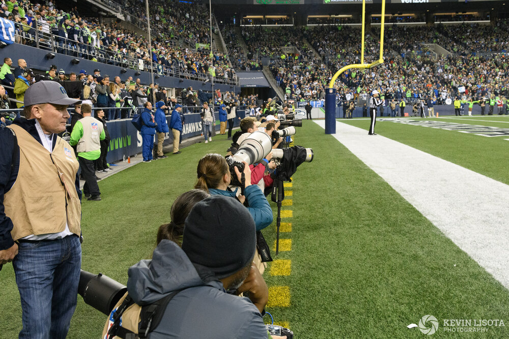 Photographers line up along the end zone