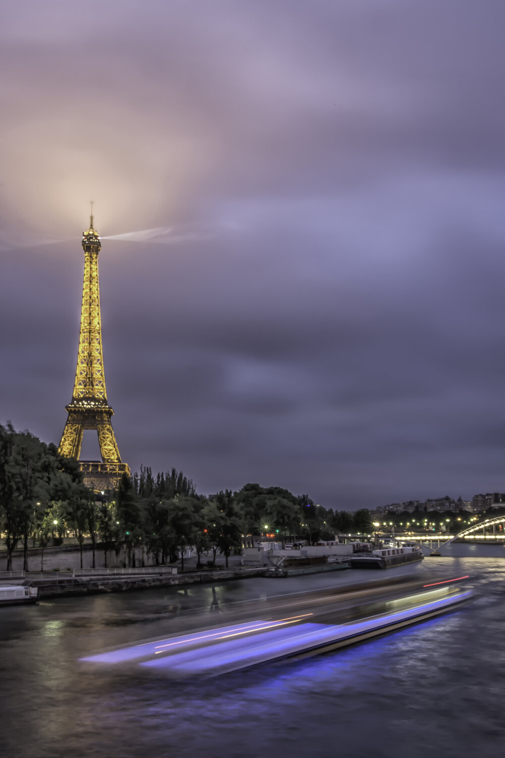 Long Exposure Paris photo - You can do this with any moving vehicle. I set the camera on a tripod and got the composition I wanted. I wanted for the boat to enter my composition and took a long exposure image. It took a few tries to figure out how many seconds it took the boat to cover the horizontal distance of my composition. Then set the camera to f8, 1/60th of a second, and got an ISO of 400 to get the proper exposure.