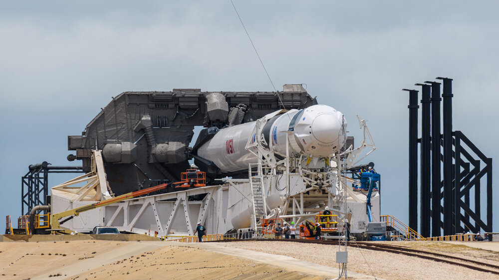 SpaceX Crew Dragon capsule at the tip of a Falcon 9 rocket as it prepares to be hoisted into vertical position