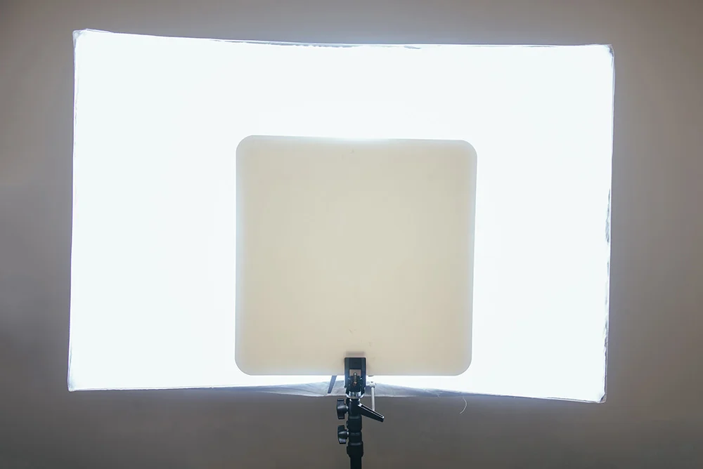 Here's a photo of my setup behind the model. I simply used a white sheet of acrylic and clamped it to the top of one of my light stands behind the model. You could use anything white but this acrylic sheet was sturdy enough to support it's own weight when clamped upright like this so made it perfect for the job.