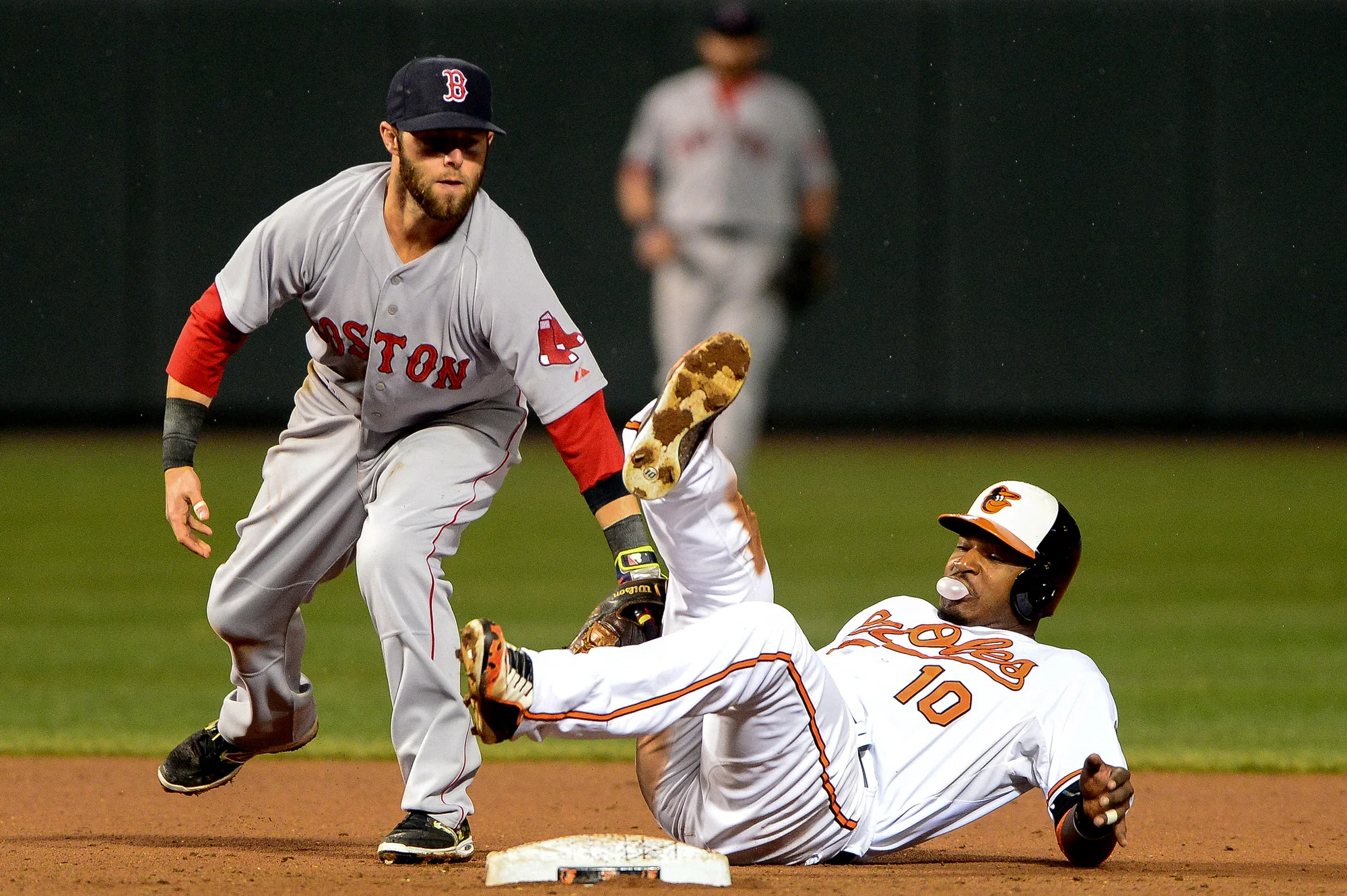 Adam Jones of the Baltimore Orioles blows a bubble after being tagged out by second baseman Dustin Pedroia of the Boston Red Sox on April 3, 2014 at Oriole Park at Camden Yards in Baltimore, Md. 