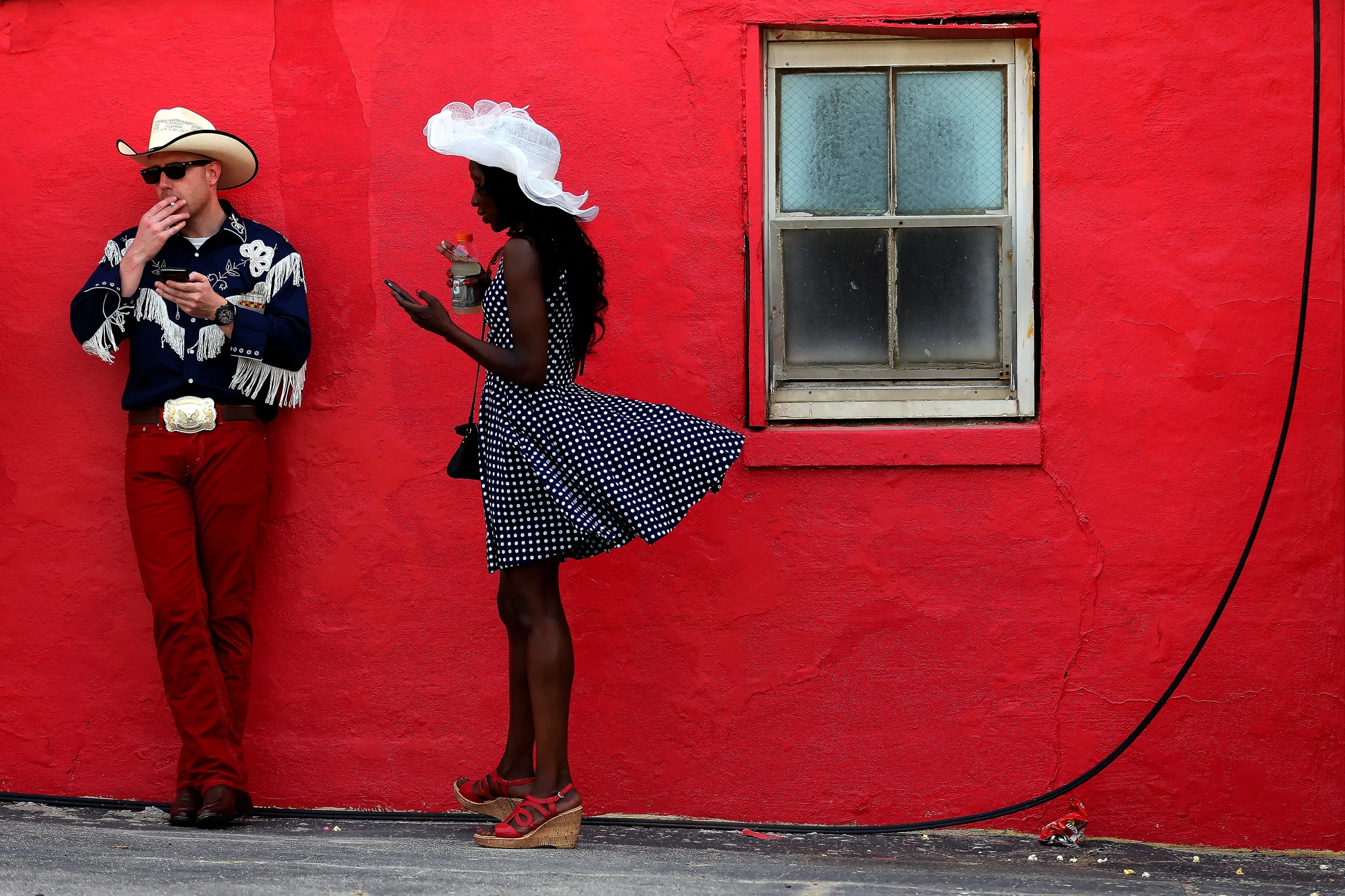 Fans smoke cigarettes and check their cell phones before the start of the 140th Preakness Stakes at Pimlico Race Course on May 16, 2015 in Baltimore, Maryland.