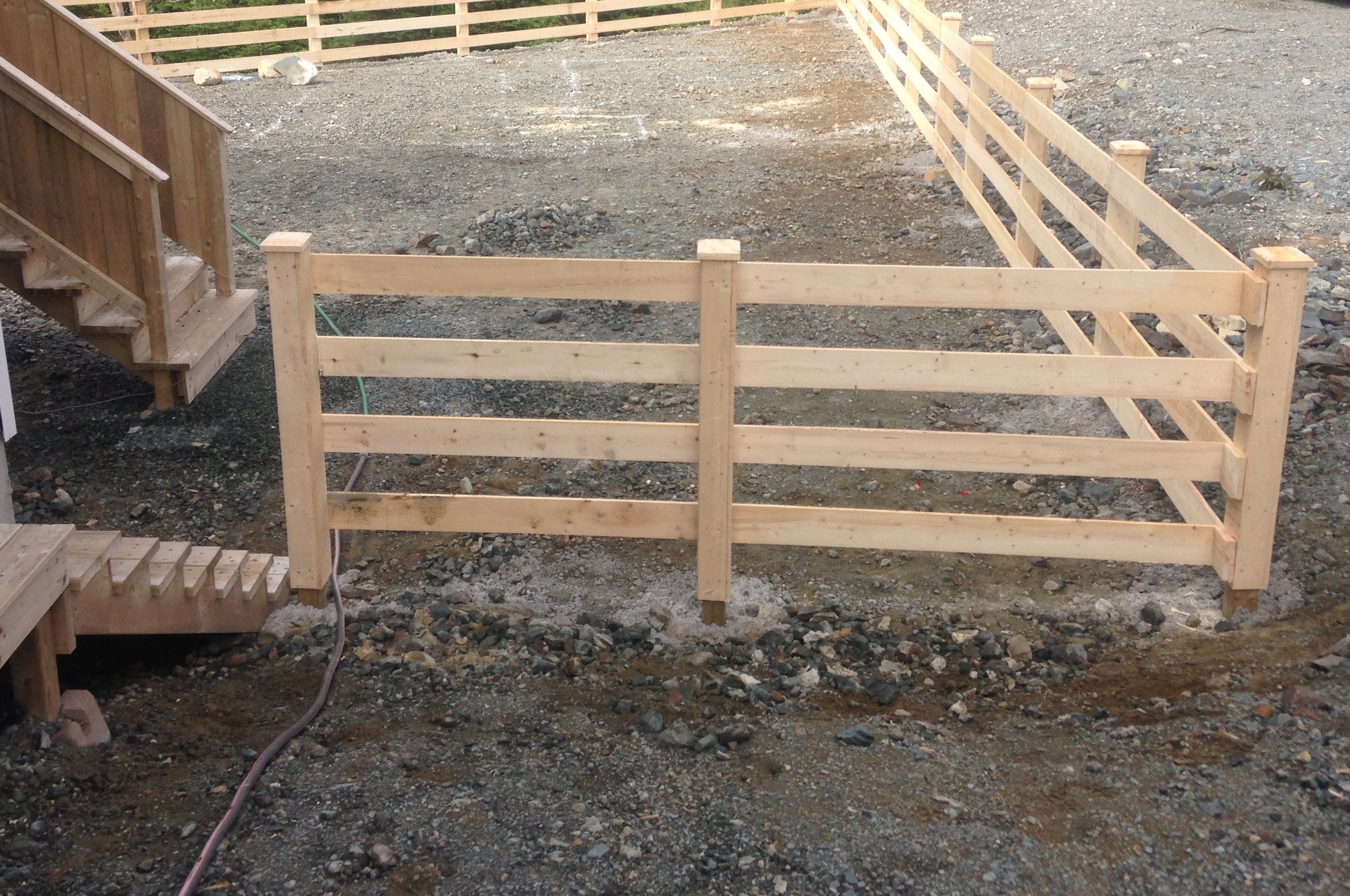 Pressure treated posts in concrete, clad with rough cut lumber and rough cut rails