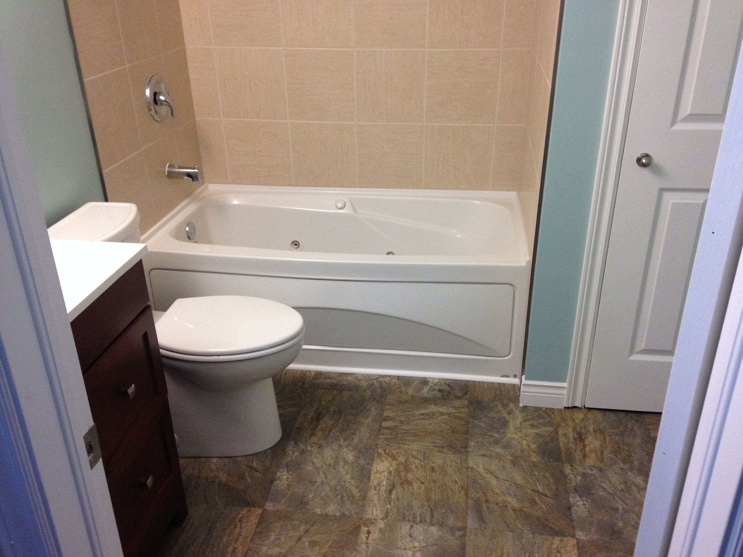 New bathtub with tiled surround, toilet and vanity