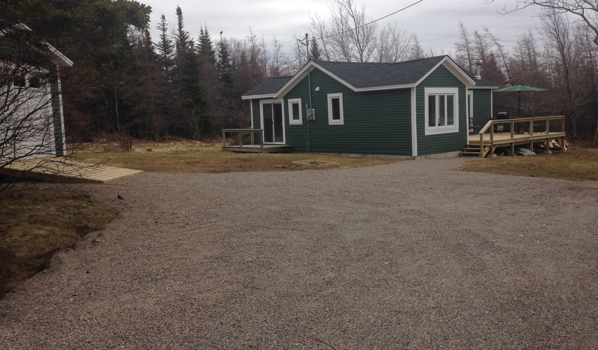 Newly graded driveway and road gravel leading to cabin and new shed