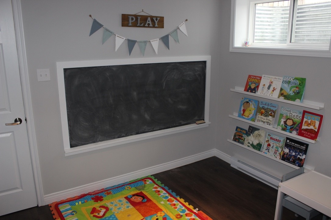 Furnished play area with chaulk board, book shelf and floor mat. 