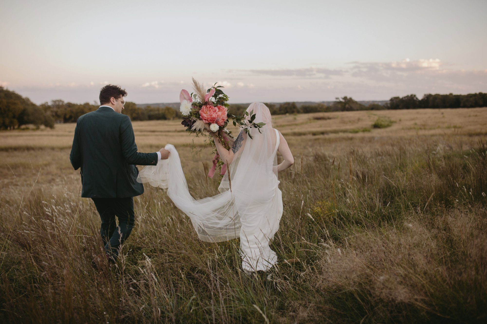 Bride with pink hair and groom in a purple suit prospect house wedding in austin tx with pastel decor and wild florals meadow