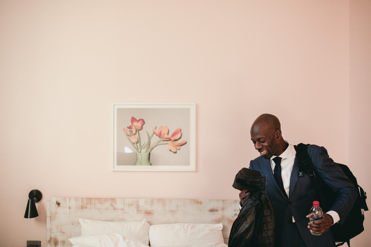Black groom in suit before elopement in Quirk Boutique Hotel room RVA Carly Romeo and CO.