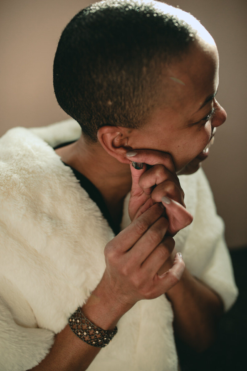 Black woman putting on earring at Quirk Hotel before wedding in Richmond VA Carly Romeo