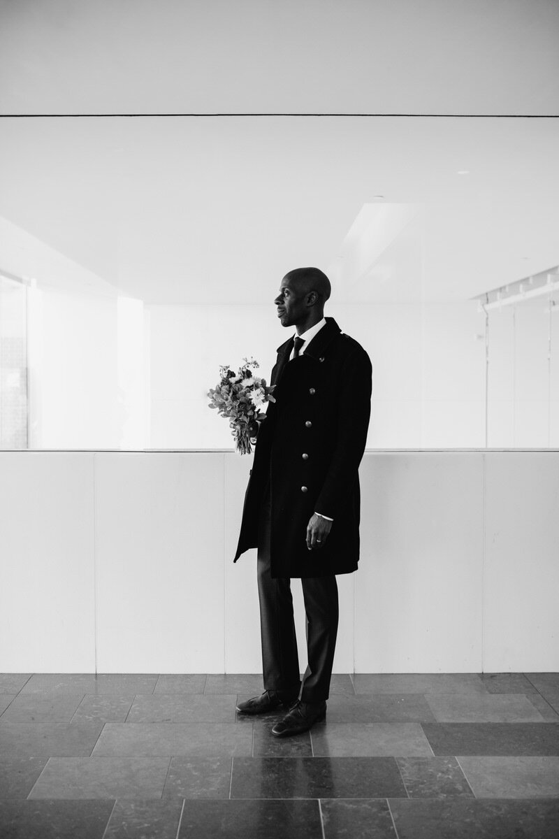  Black Man holding flower bouquet on wedding day, black and white, at the Virginia Museum of Fine arts in RVA, Photo by Carly Romeo + Co. 