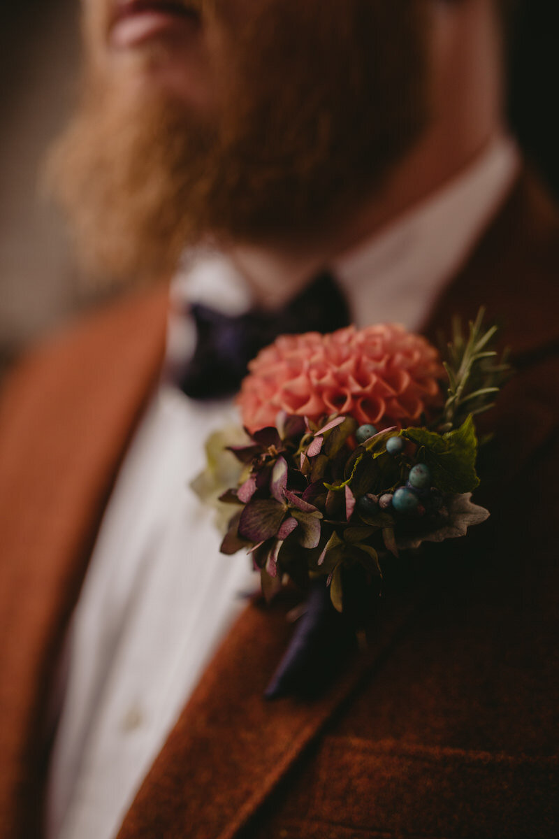 Groom wearing rust orange suit and boutonniere at autumn wedding in Baltimore glass blowing studio Carly Romeo &amp; Co.