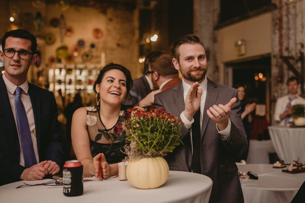 Friends clapping at wedding reception in the Corradetti Glassblowing studio Baltimore MD Carly Romeo