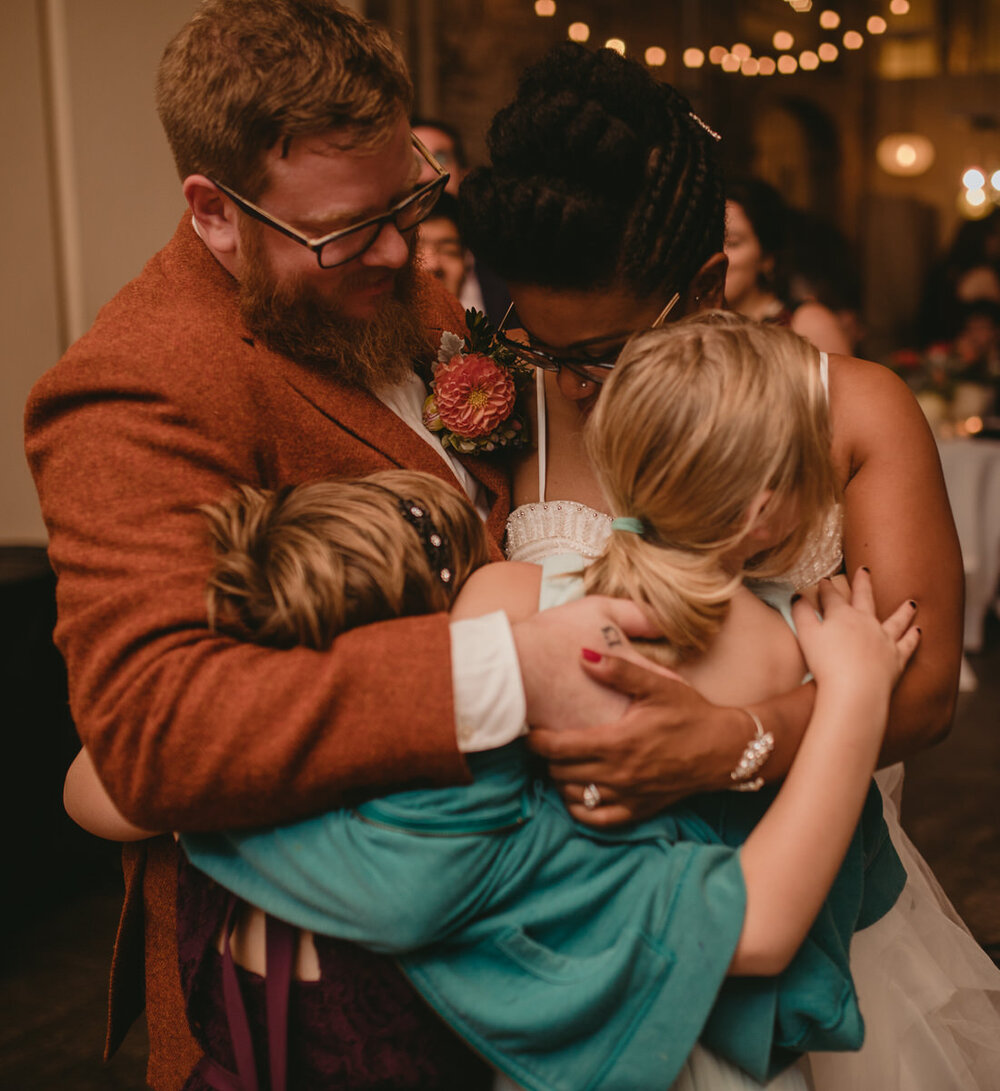 Newlywed couple hugging children at Corradetti Glassblowing Studio Wedding photography Carly Romeo