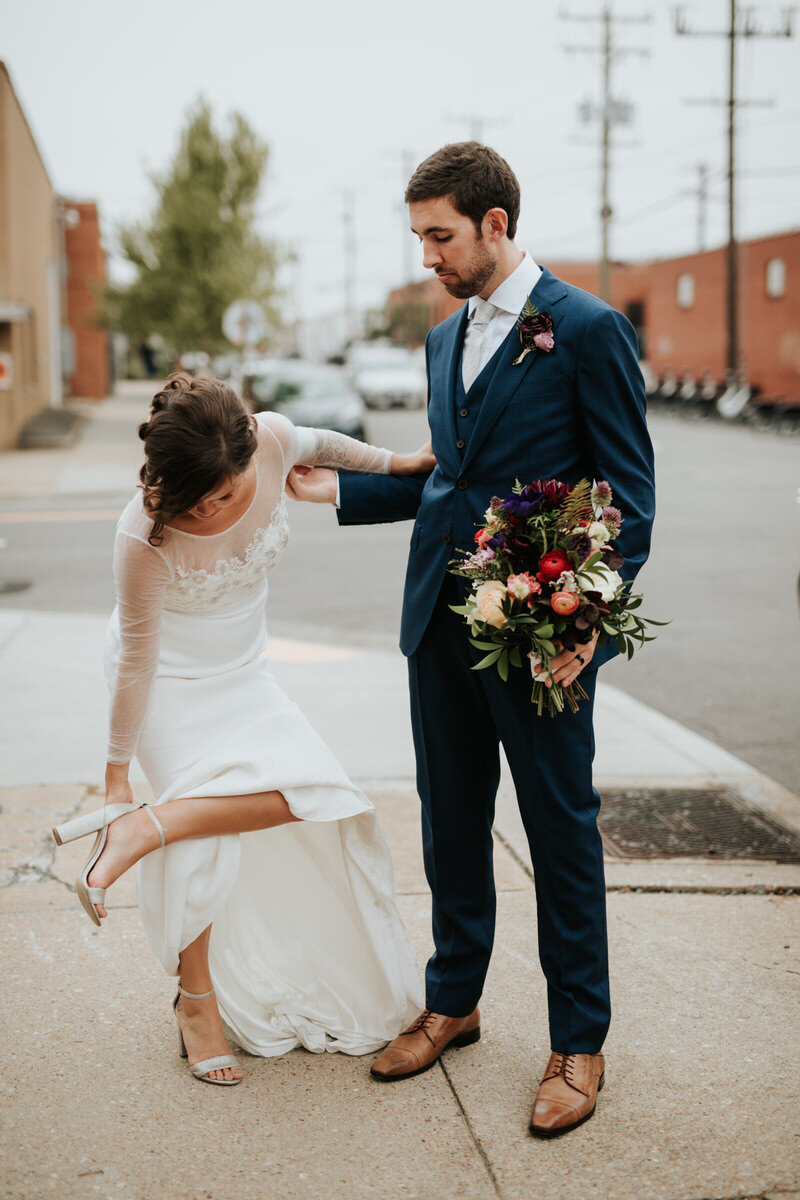 Newly wed couple bride fixing shoe outside Studio Two Three RVA Carly Romeo