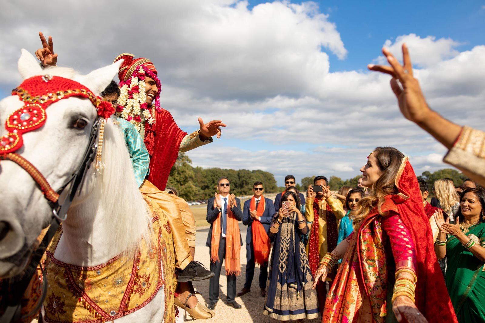 Groom on horse smiling at bride in traditional Baraat at Dover Hall Richmond VA Carly Romeo + Co.