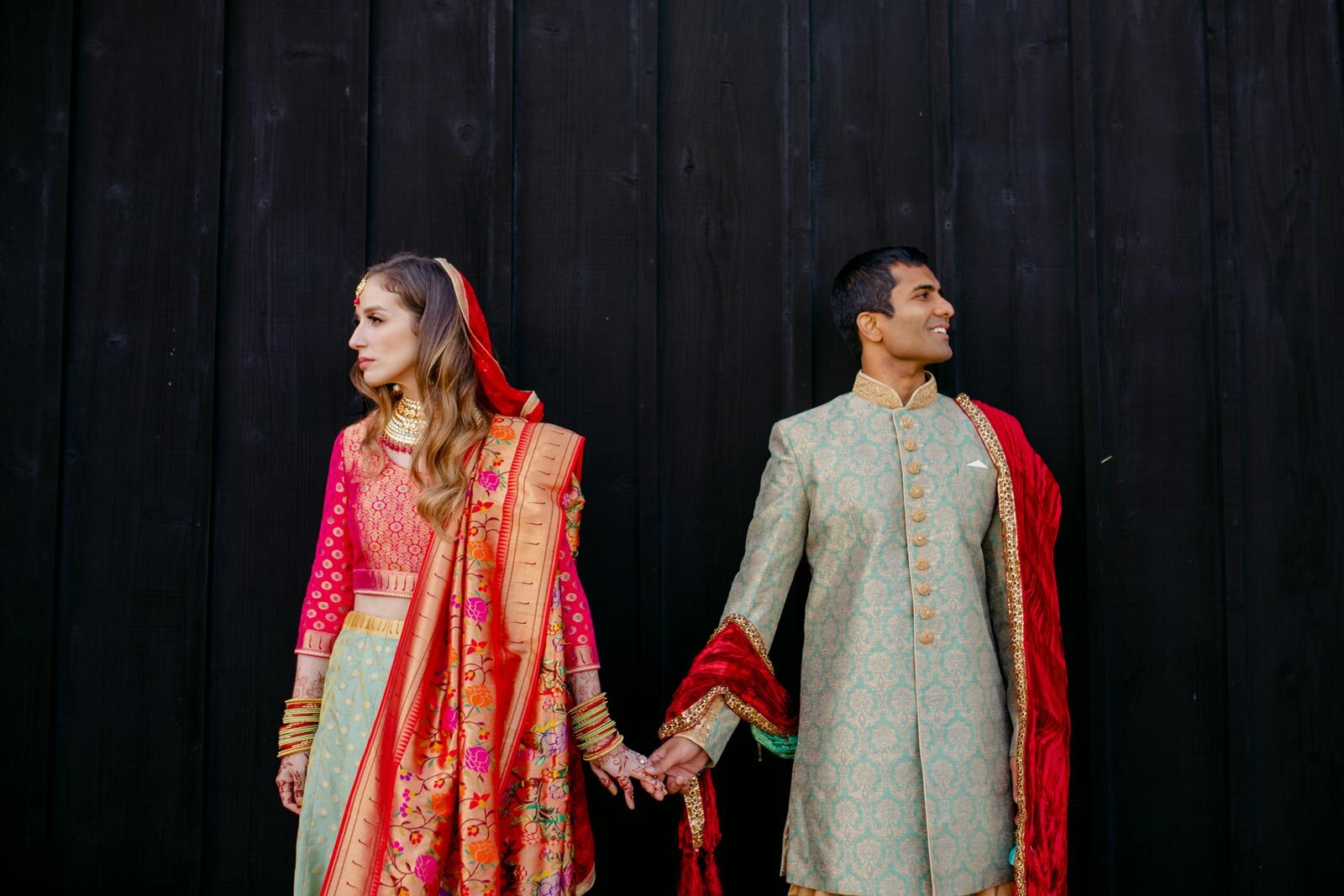 Couple holding hands in tradtional indian wedding attire before charred wall at Dover Hall RVA Carly Romeo