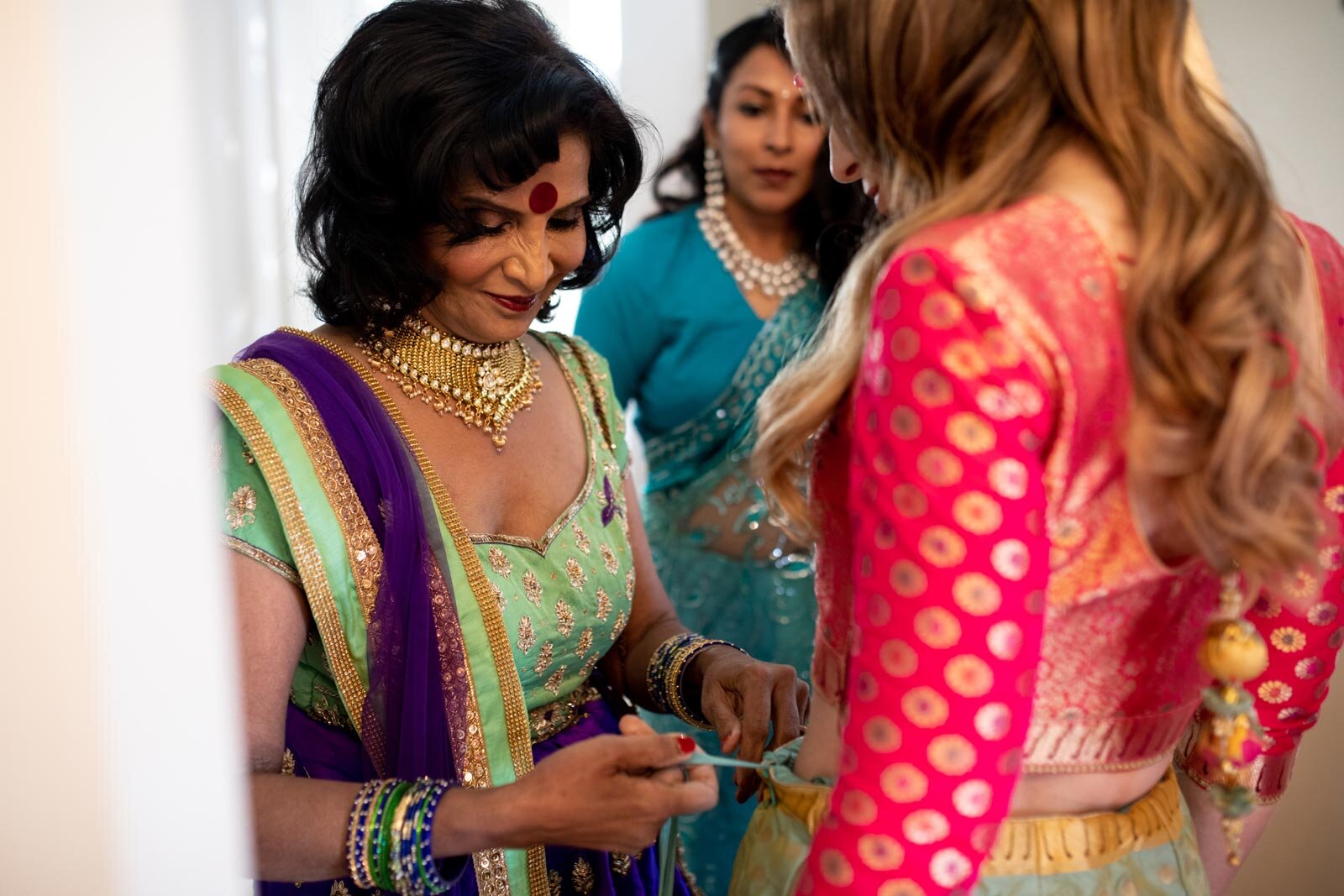 Mother of the groom dressing bride in traditional indian wedding dress at Dover Hall Richmond Carly Romeo
