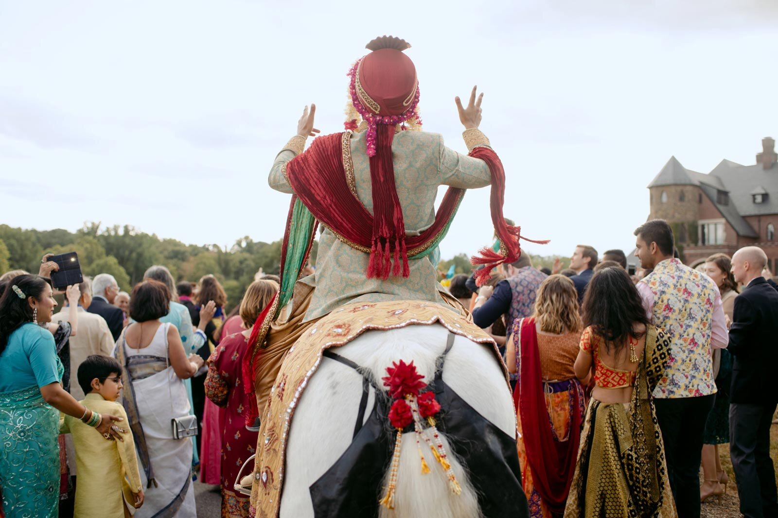 Indian groom on horse in Baraat ceremony at Dover Hall Richmond VA Carly Romeo wedding photography