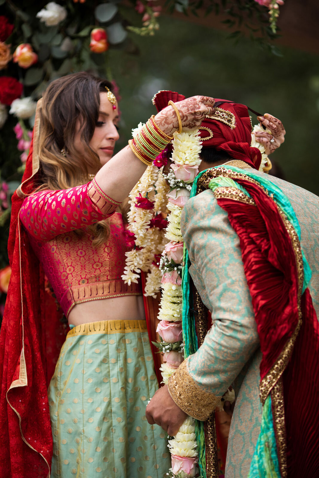 Bride placing flower garland on groom in traditional indian wedding at Dover Hall Richmond VA Carly Romeo