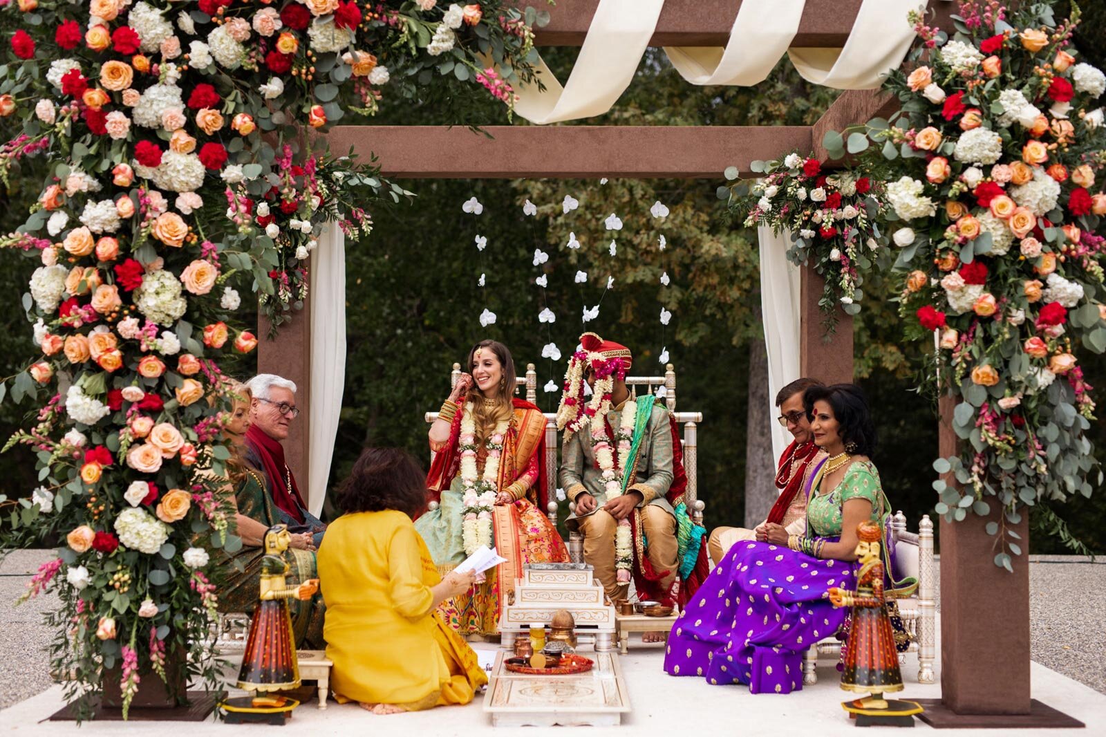 Bride and groom with parents seated in traditional mandap at Dover Hall wedding RVA Carly Romeo and Co.