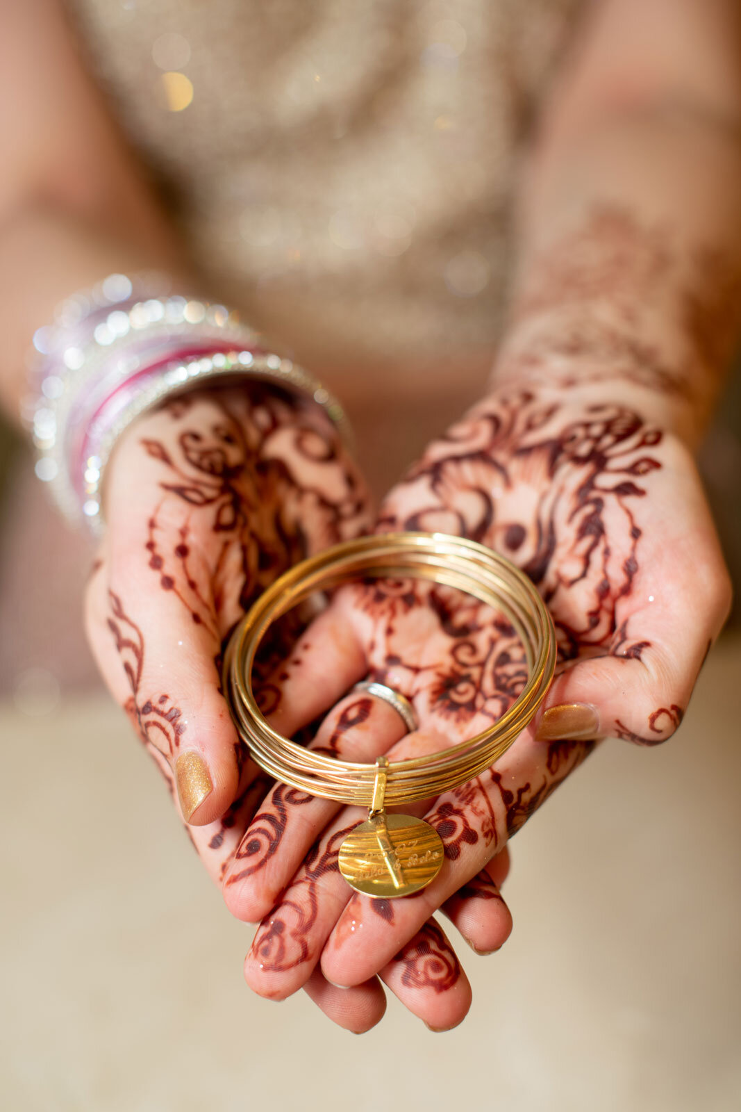 Bride holding gold bangles with traditional wedding henna at Dover Hall RVA Carly Romeo + Co.