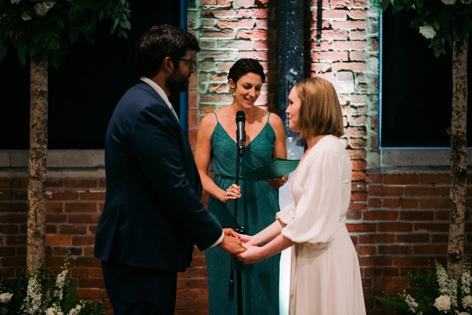 Bride and groom holding hands before officiant at Pittsburgh Opera PA Carly Romeo