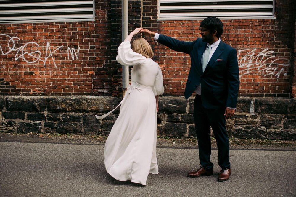 Bride and groom dancing before graffiti brick wall in Pittsburgh Pennsylvania Carly Romeo + Co.