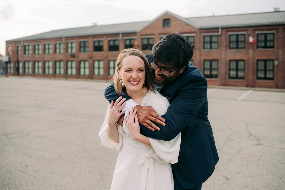 Newly web mixed race couple embracing before brick building in Pittsburgh PA Carly Romeo &amp; Co.
