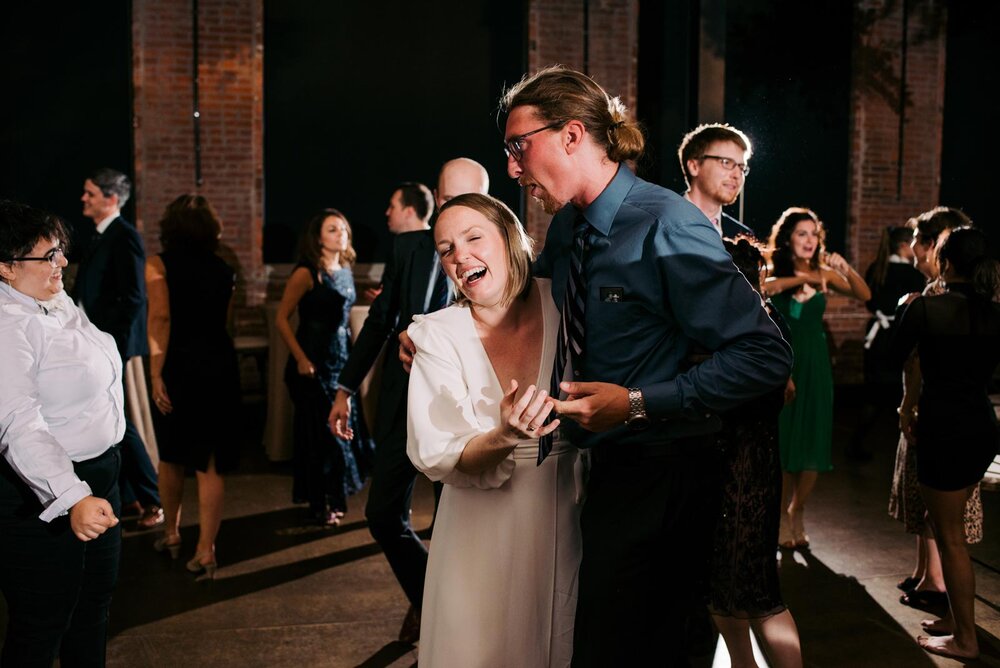 Bride laughing and dancing with tall wedding guest at Pittsburgh Opera PA Carly Romeo + Co.