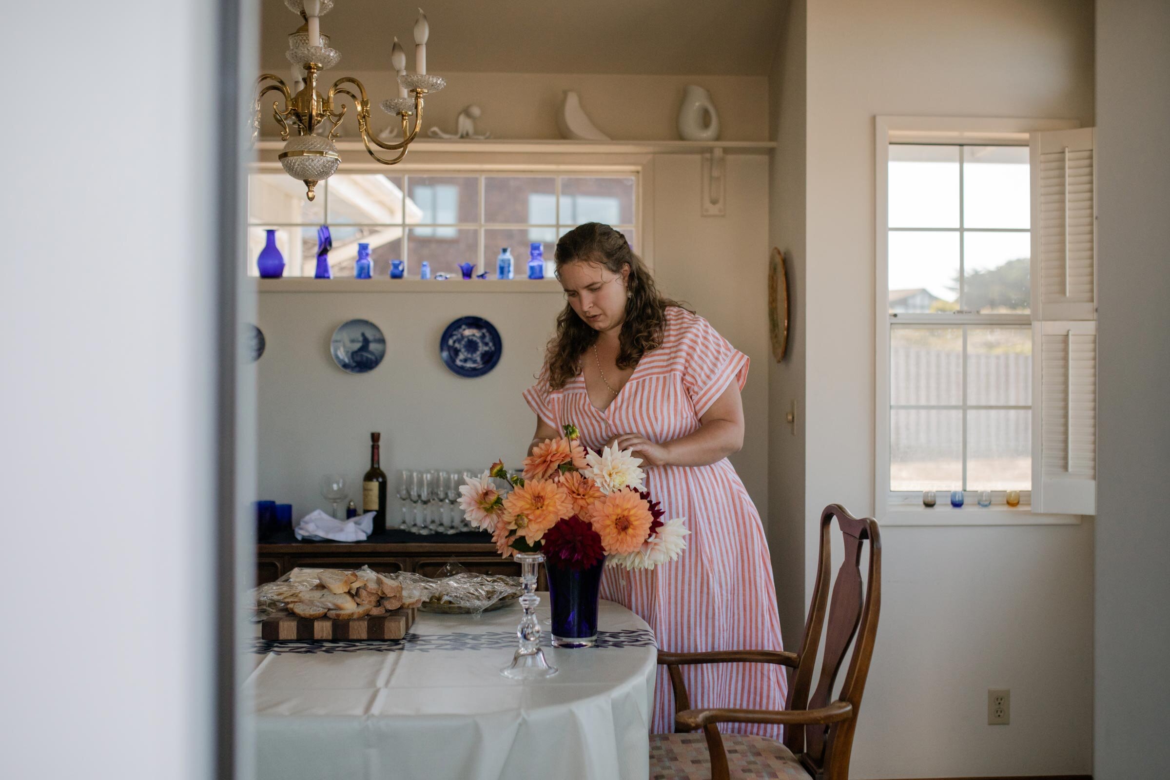 Wedding guest arranging flowers in dinning room in Mendocino CA Carly Romeo &amp; Co.