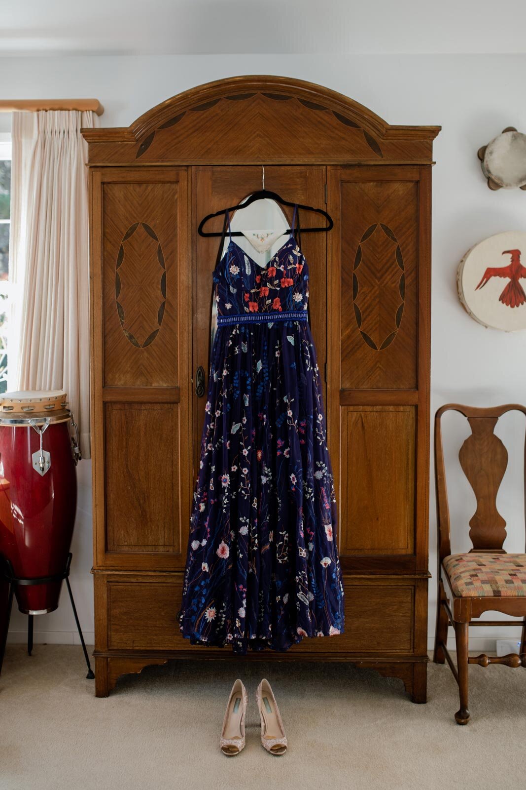 Blue wedding dress with colorful floral embroidery hanging from an armoire in Mendocino CA Carly Romeo
