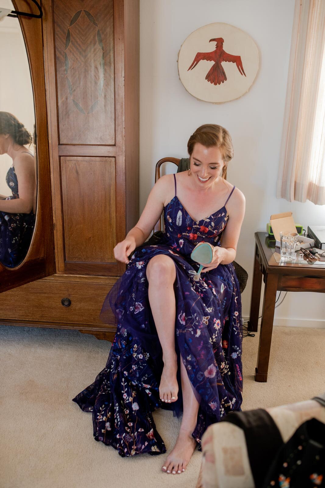 Woman sitting in blue floral wedding dress putting on shoes in Mendocino CA Carly Romeo
