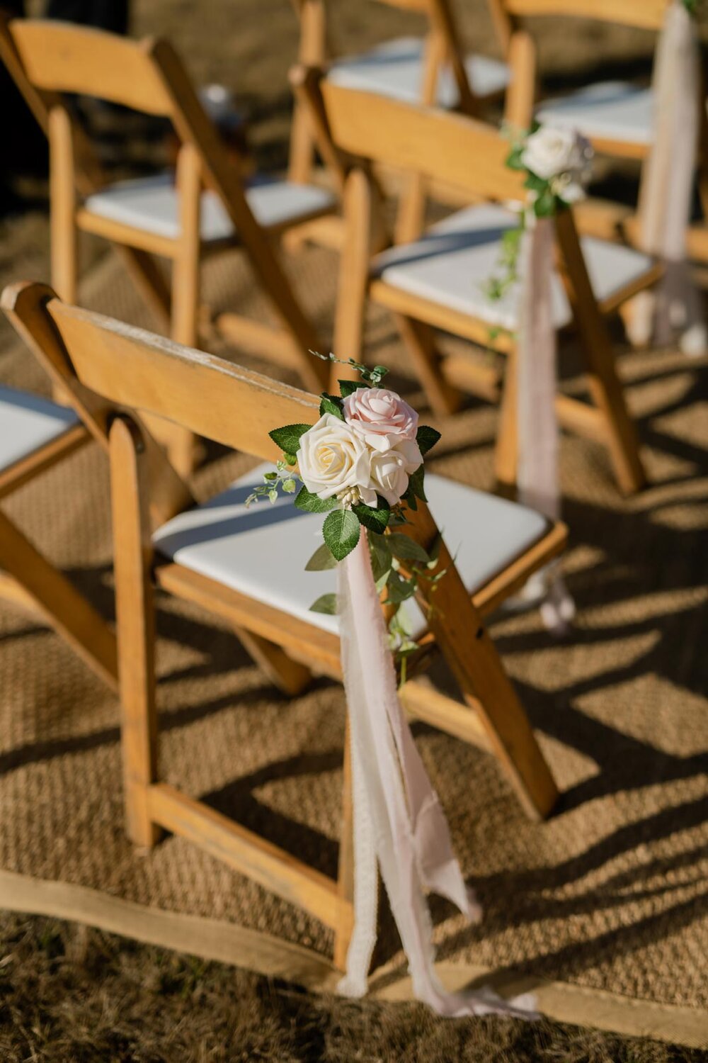 Soft pink and white flowers tied to guest chairs with ribbon in Mendocino CA Carly Romeo and Co.