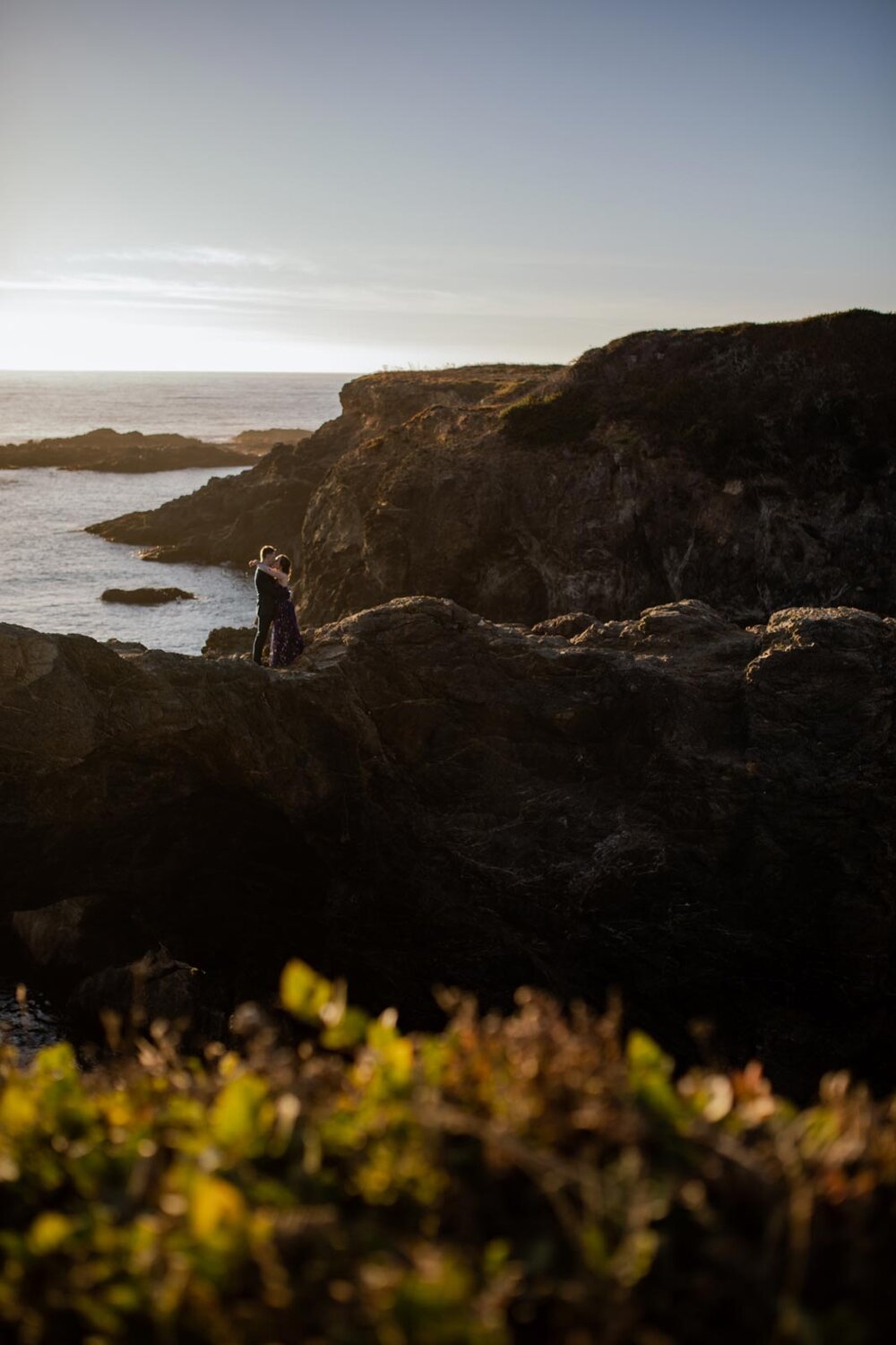 Newlywed couple embracing on rocky cliffs beside the ocean in Mendocino CA Carly Romeo and Co