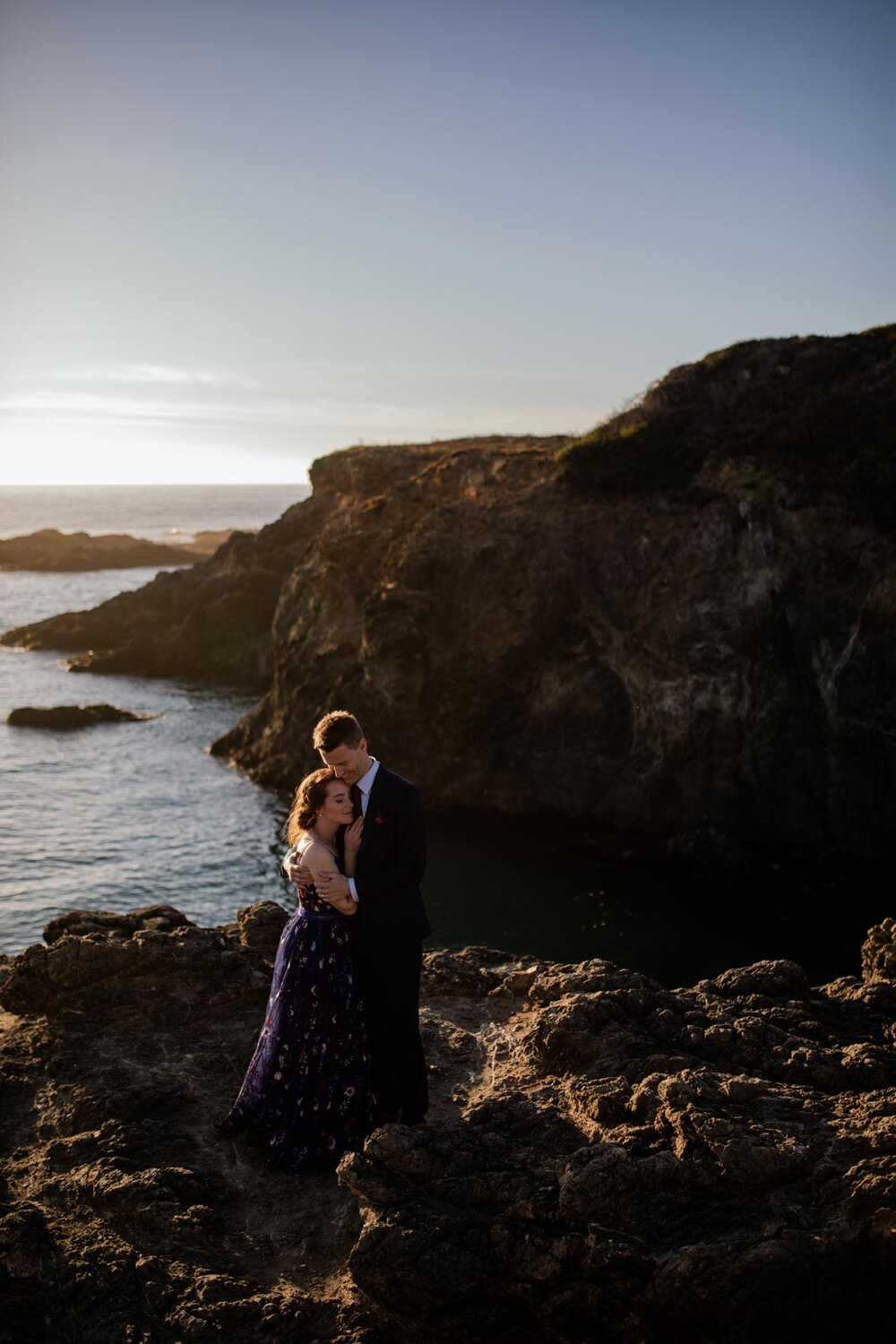 Newlywed couple embracing on rocky cliffs beside the ocean in Mendocino CA Carly Romeo &amp; Co.