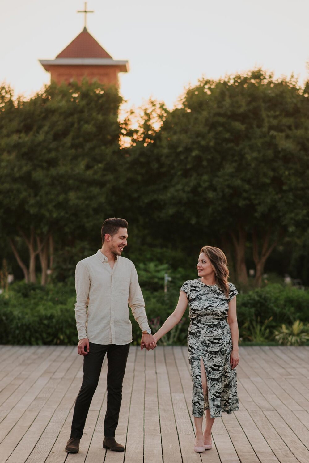 Latinx engaged couple holding hands before greenery and a church's steeple in RVA Carly Romeo and Co. (Copy)