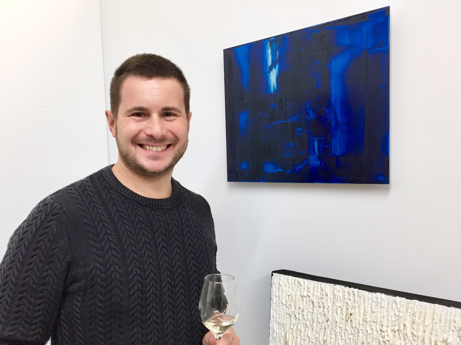 L'artiste Louis-Bernard St-Jean, devant l'une de ses nouvelles œuvres sur aluminium, avec un verre de vin à la main