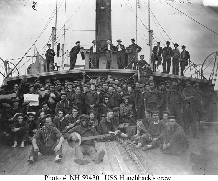 Crew of USS Hunchback during the American Civil War. The crewman to the left of the man holding a newspaper is with a small dog.
