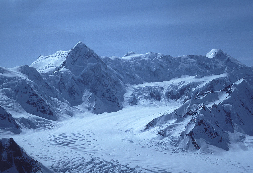 Mount Kennedy as shown from an airplane in 1984. Mount Kennedy is the high peak towards the left. Source: Gary Clark, available here .