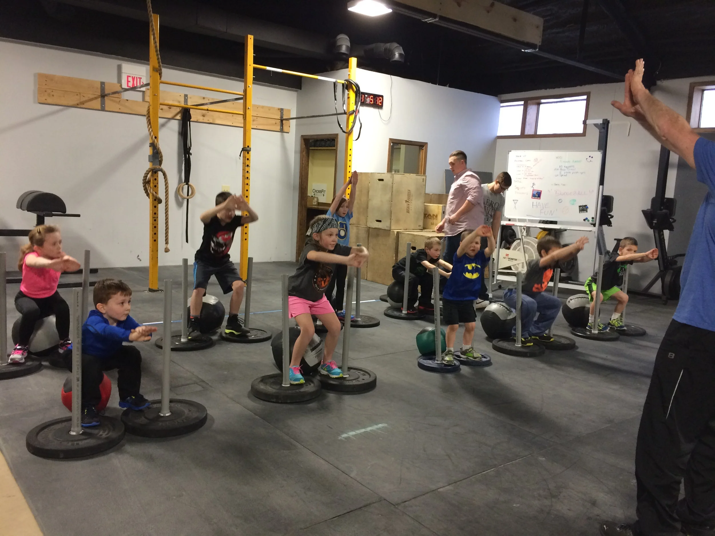 Coach Mike leading on our Rock Star CrossFit Kids on proper Squat form.