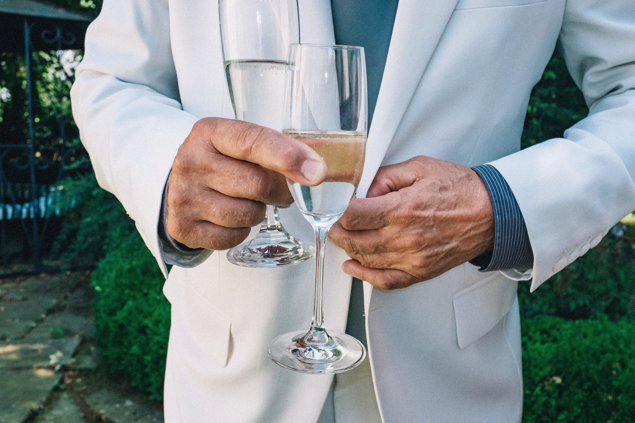 Groom's father unbuttoning his white jacket