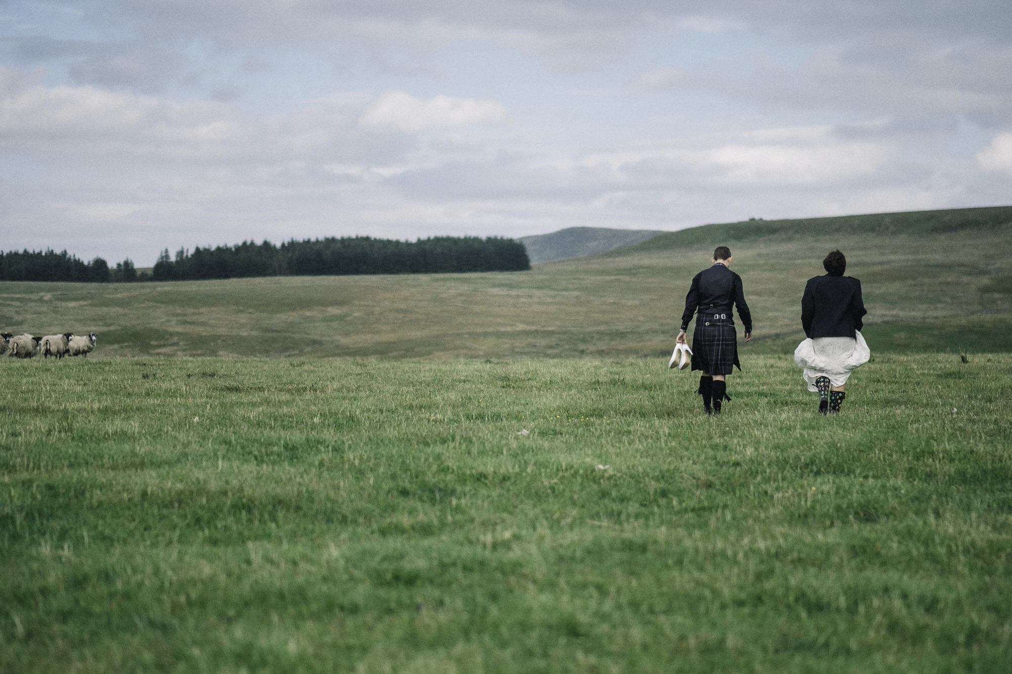 Bride + groom walking in a field