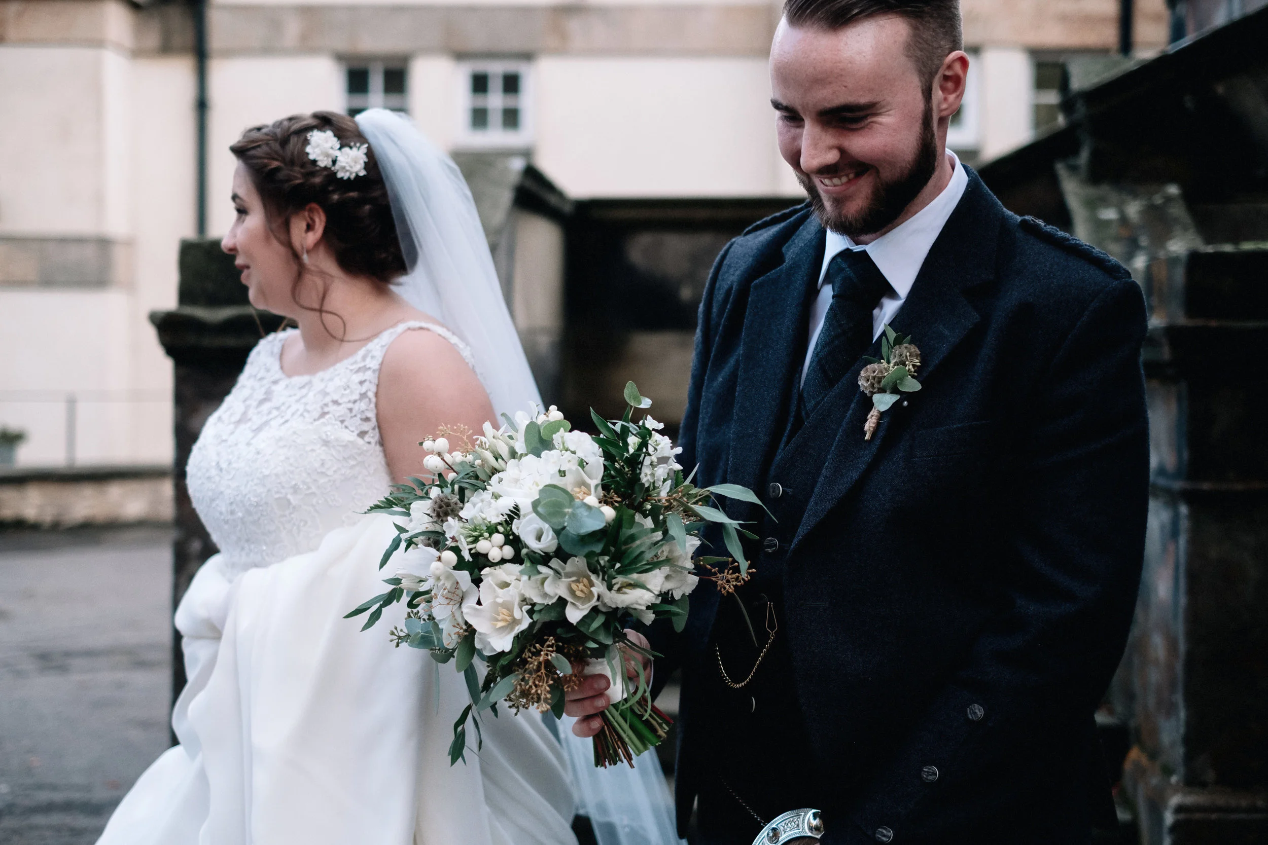 Groom carries his bride's flowers