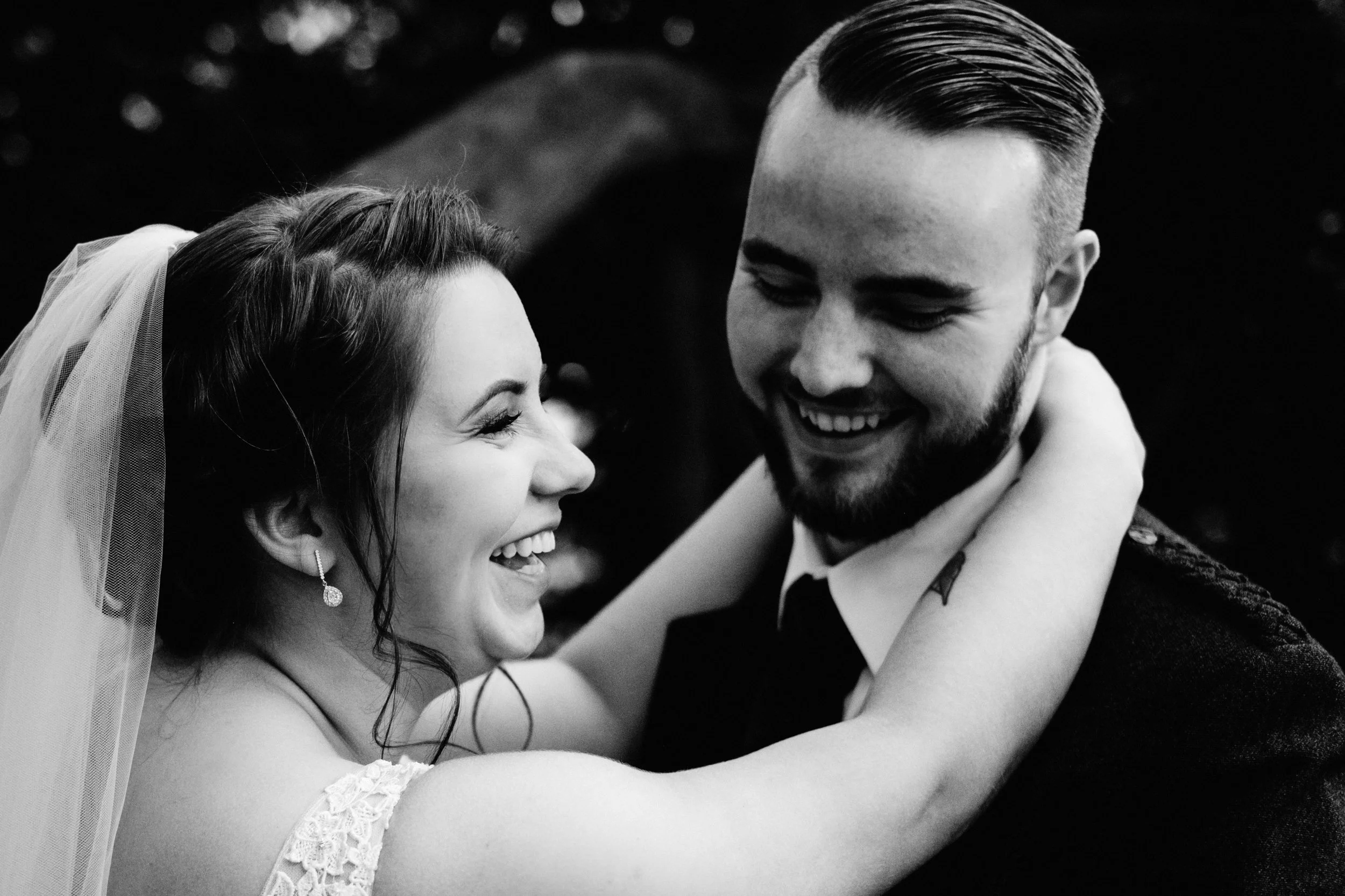 Bride and groom laugh in an embrace
