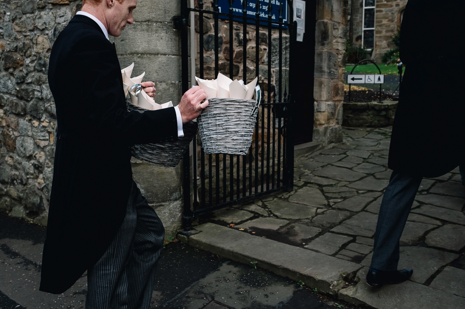 groomsman carrying two containers of rose petails for confetti throw later
